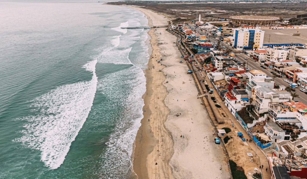 Aerial view of Tijuana's picturesque beach, with pristine sands and the serene Pacific Ocean stretching to the horizon, while seagulls dot the sky.